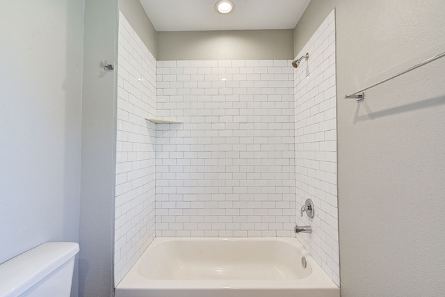 bathroom with toilet and tiled shower / bath combo