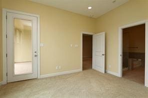 unfurnished bedroom with ensuite bath and light colored carpet