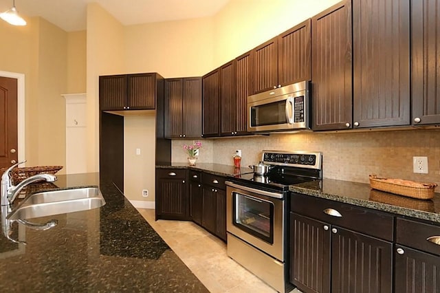 kitchen with appliances with stainless steel finishes, sink, backsplash, dark stone counters, and dark brown cabinets