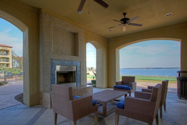 view of patio with a tile fireplace, ceiling fan, and a water view