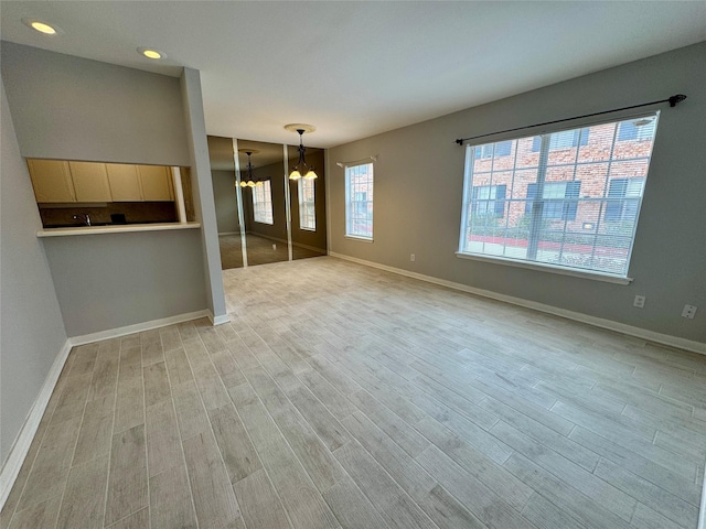 unfurnished living room featuring an inviting chandelier and light wood-type flooring