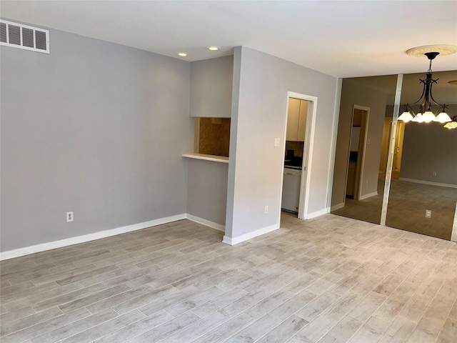 spare room featuring a chandelier and light hardwood / wood-style floors