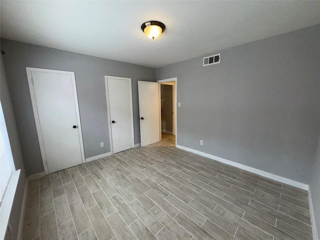 unfurnished bedroom featuring light hardwood / wood-style flooring and two closets