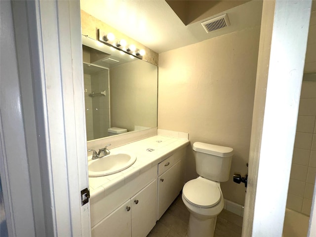 bathroom with vanity, tile patterned floors, toilet, and a tile shower