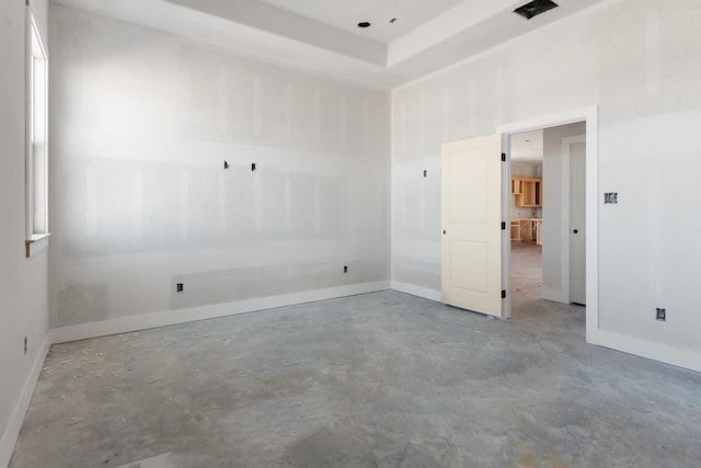 spare room with concrete flooring and a raised ceiling