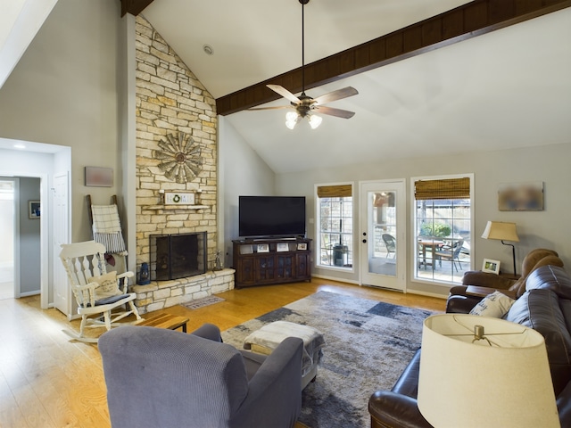 living room featuring a stone fireplace, high vaulted ceiling, ceiling fan, beam ceiling, and light hardwood / wood-style floors