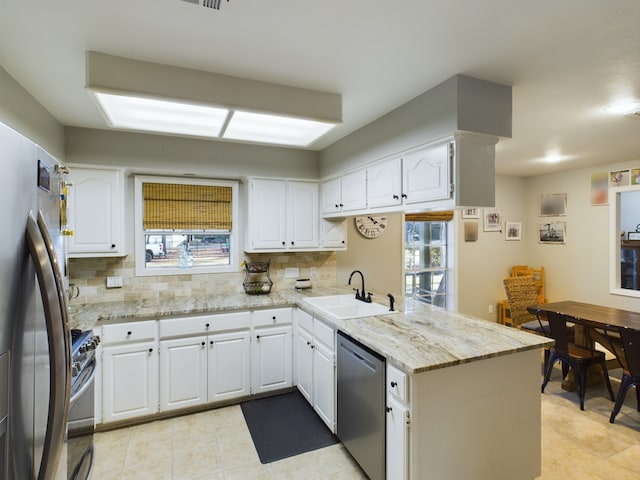 kitchen featuring stainless steel appliances, white cabinetry, sink, and kitchen peninsula