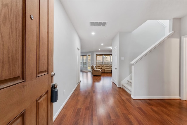 entryway with stairs, dark wood-style floors, visible vents, and baseboards