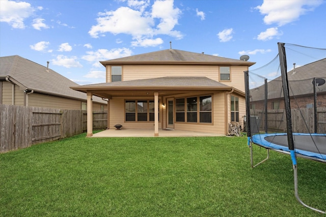 rear view of property with a patio, a trampoline, a fenced backyard, and a lawn