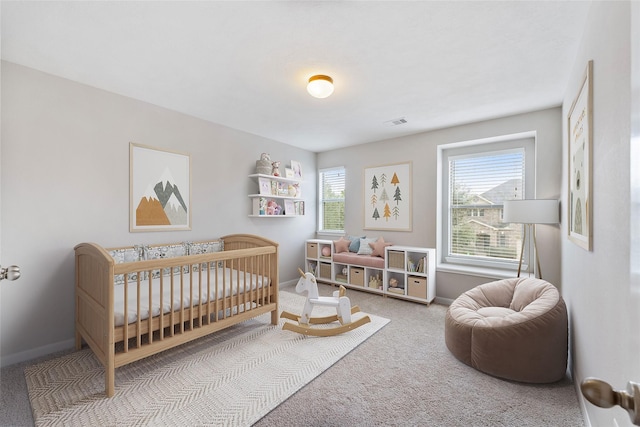 bedroom with a crib, carpet flooring, visible vents, and baseboards