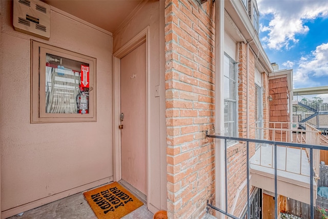 property entrance with brick siding and a balcony