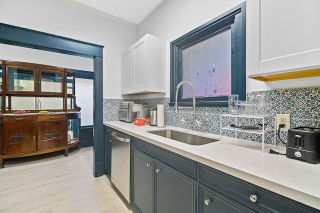 kitchen featuring sink, light hardwood / wood-style flooring, dishwasher, white cabinets, and decorative backsplash