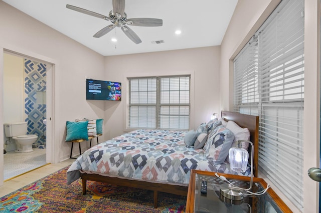 bedroom featuring ceiling fan, connected bathroom, hardwood / wood-style floors, and multiple windows