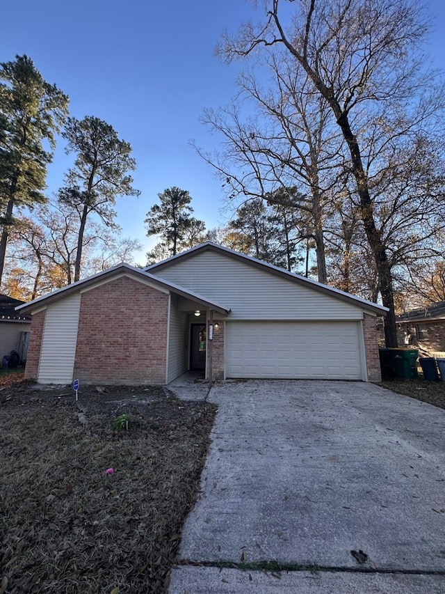 mid-century home with brick siding, an attached garage, and driveway