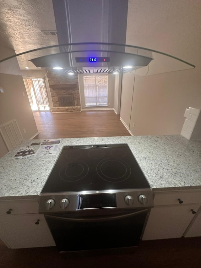 kitchen with island range hood, light stone countertops, hardwood / wood-style floors, and electric range