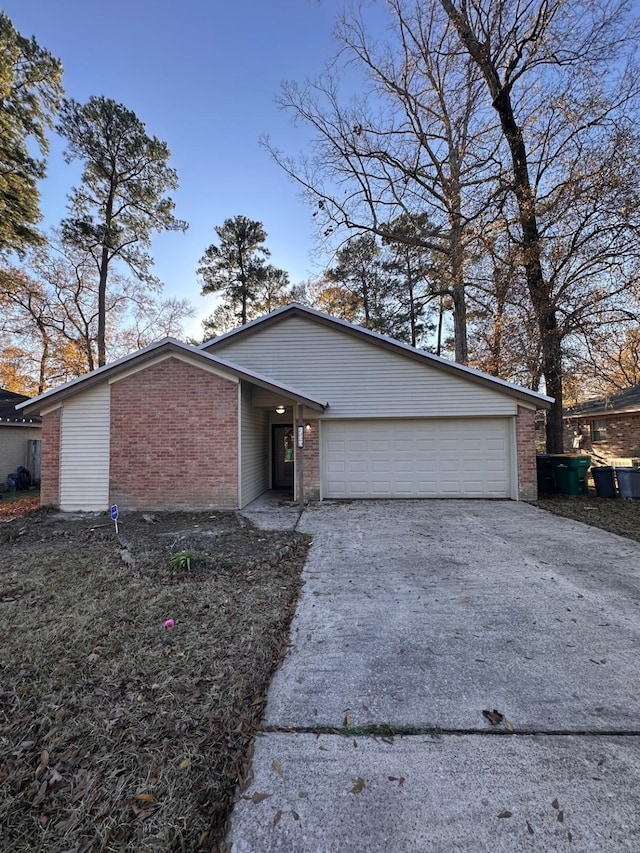 mid-century home with brick siding, an attached garage, and driveway