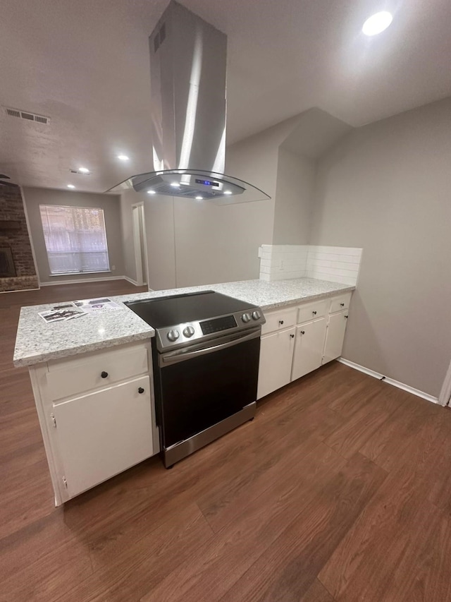 kitchen with stainless steel electric range, island range hood, light stone countertops, white cabinets, and dark hardwood / wood-style flooring