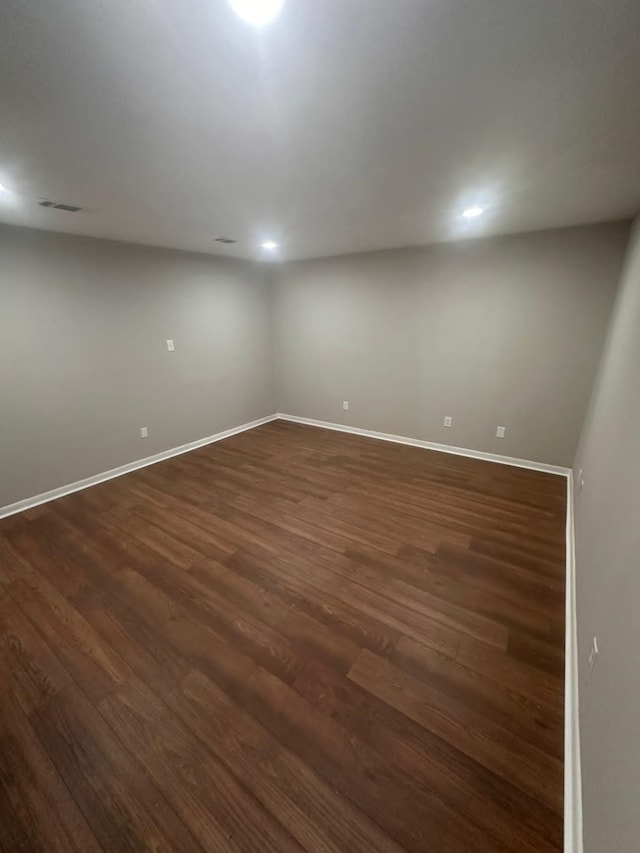 below grade area with visible vents, baseboards, and dark wood-style flooring