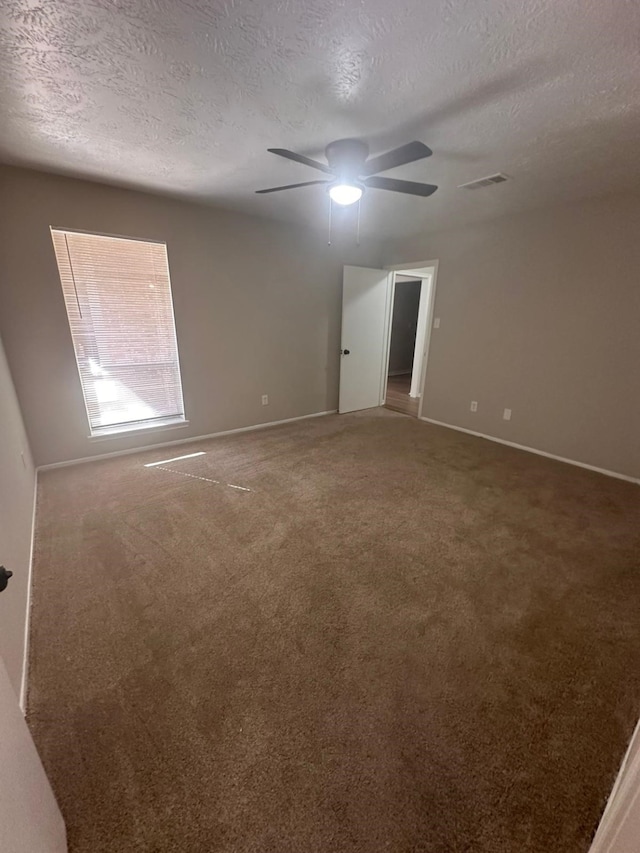 carpeted empty room featuring visible vents, baseboards, a textured ceiling, and a ceiling fan