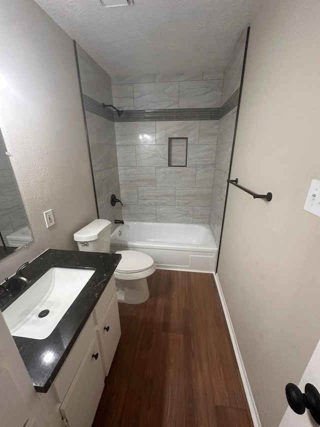 bathroom featuring toilet, shower / bath combination, vanity, wood finished floors, and a textured ceiling