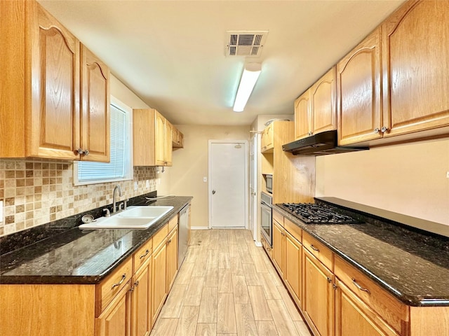 kitchen featuring sink, light hardwood / wood-style flooring, appliances with stainless steel finishes, dark stone countertops, and tasteful backsplash