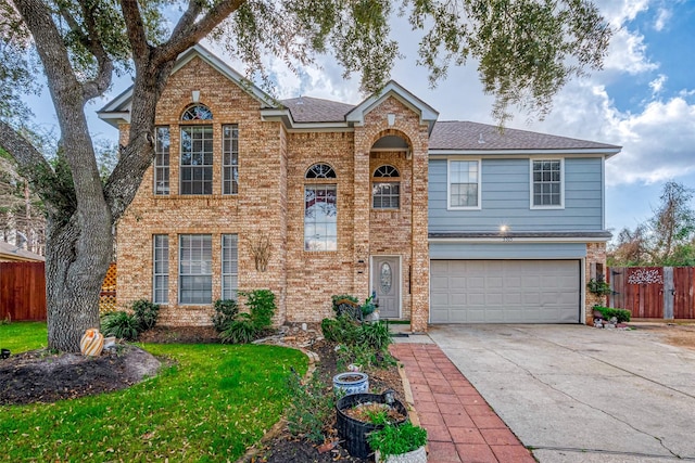 traditional-style home featuring concrete driveway, brick siding, an attached garage, and fence