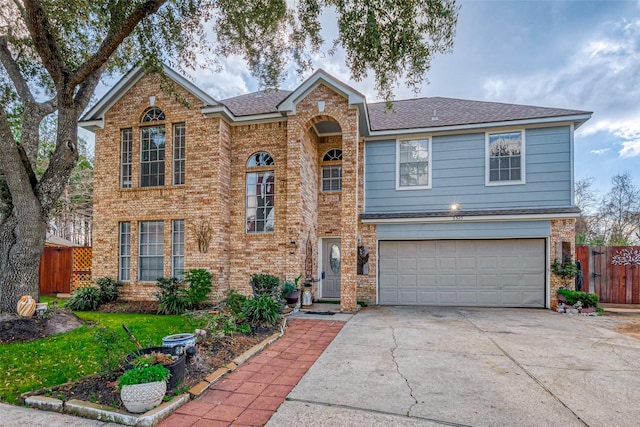 traditional-style house with concrete driveway, brick siding, fence, and an attached garage