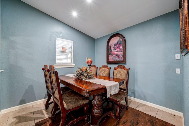 dining room with lofted ceiling, tile patterned flooring, and baseboards