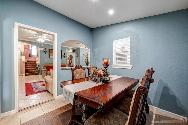 dining room with stairway, light tile patterned floors, arched walkways, and ornamental molding