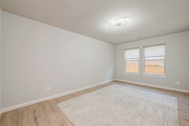 spare room with light hardwood / wood-style floors and a textured ceiling