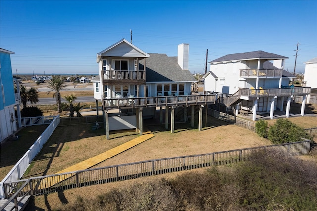 rear view of house with a balcony and a yard