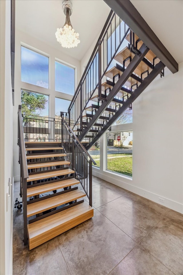 stairs featuring concrete flooring, a healthy amount of sunlight, and an inviting chandelier