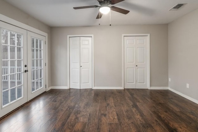 unfurnished bedroom with ceiling fan, access to exterior, dark hardwood / wood-style floors, two closets, and french doors