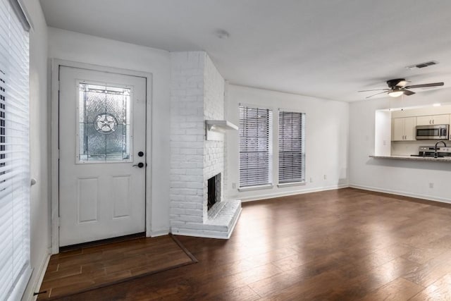 entryway featuring dark wood-type flooring, ceiling fan, and a fireplace