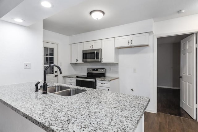 kitchen with dark wood-type flooring, sink, appliances with stainless steel finishes, white cabinets, and backsplash