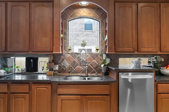 kitchen with stainless steel dishwasher, dark stone countertops, sink, and backsplash