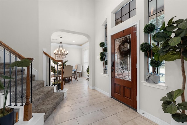 tiled entrance foyer featuring a notable chandelier, a wealth of natural light, and a high ceiling