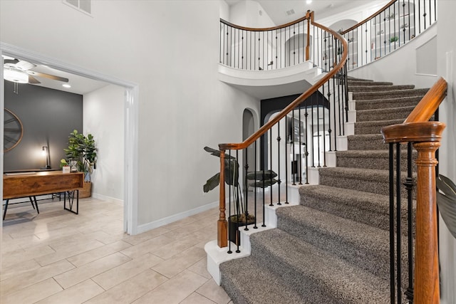 staircase with ceiling fan and a high ceiling