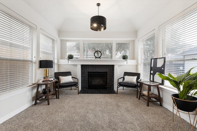 sitting room with a tiled fireplace, vaulted ceiling, and carpet