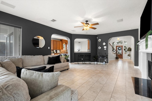 tiled living room featuring a textured ceiling and ceiling fan