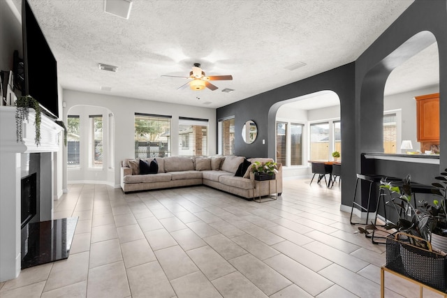 tiled living room with ceiling fan and a textured ceiling