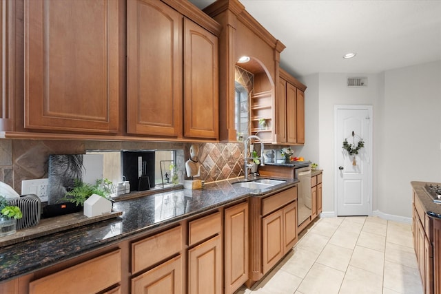 kitchen featuring sink, light tile patterned floors, dishwasher, dark stone countertops, and decorative backsplash