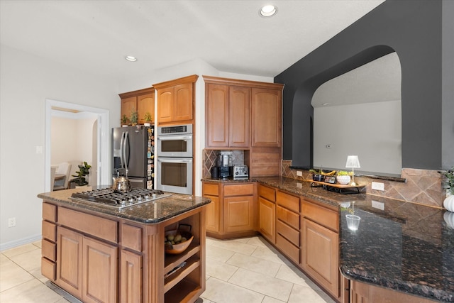 kitchen with tasteful backsplash, stainless steel appliances, kitchen peninsula, and light tile patterned flooring