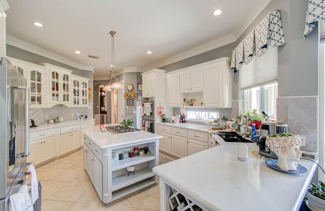 kitchen with pendant lighting, sink, white cabinets, and a kitchen island