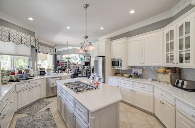 kitchen with appliances with stainless steel finishes, hanging light fixtures, a center island, tasteful backsplash, and white cabinets