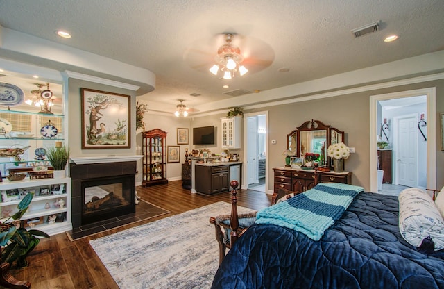 bedroom featuring ornamental molding, dark hardwood / wood-style flooring, a tiled fireplace, and a textured ceiling