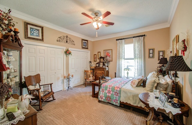 carpeted bedroom with crown molding, ceiling fan, a textured ceiling, and two closets