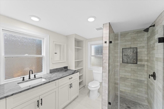 bathroom featuring vanity, toilet, a shower with door, and built in features