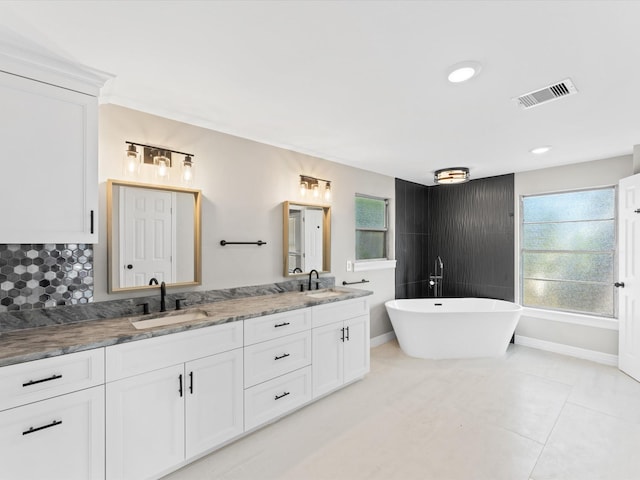 bathroom with tasteful backsplash, vanity, tile patterned floors, and a tub to relax in