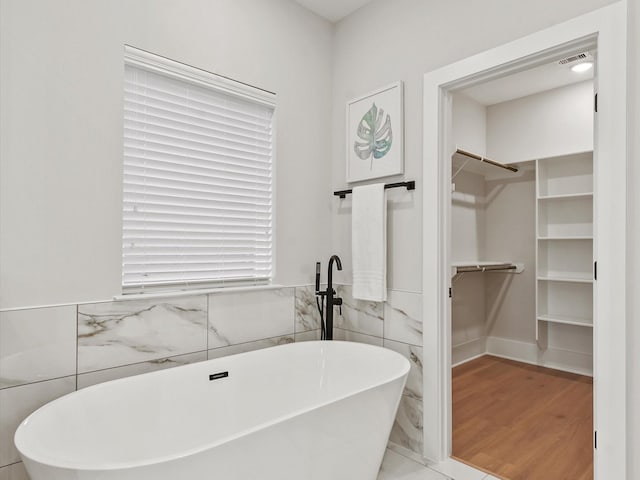 bathroom with wood-type flooring, tile walls, and a washtub